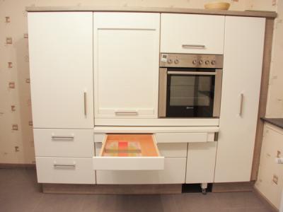 Schublade in eingebauter Tischplatte; Tischplatte in Ruheposition; darüber Rollo mit Holzlamellen in Frontfarbe